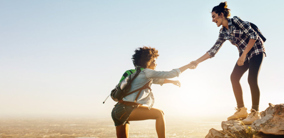 One hiker helping another hiker climb to the top.